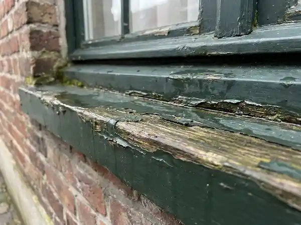 Onderregel van een houten raam met loskomende lak